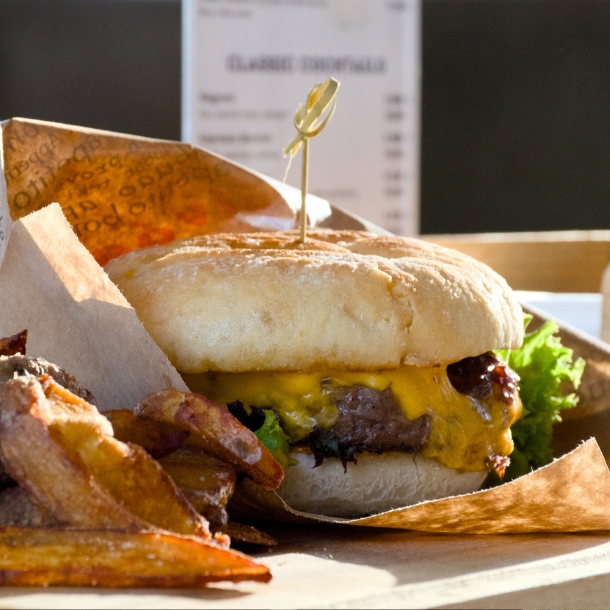Mouth-watering craft burger with a juicy patty, melted cheese, and crispy potato wedges served at Vogue Boat Restaurant in Budapest.