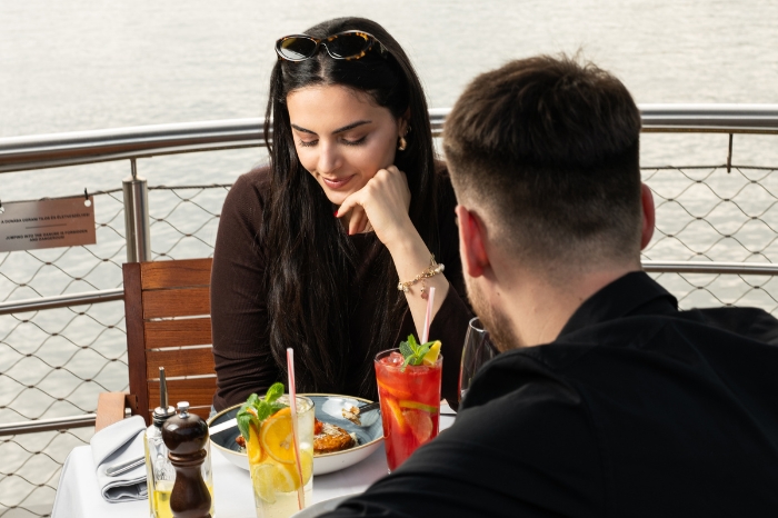 Romantic dining on the Danube: a couple enjoying refreshing lemonades and delicious food on the terrace of the Vogue Boat Restaurant in Budapest.